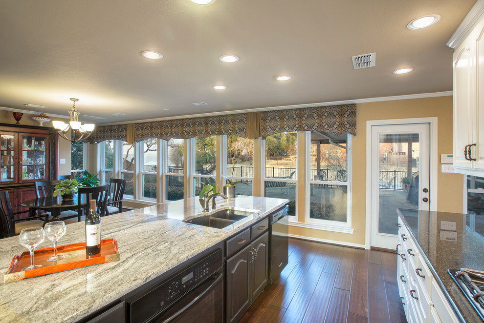 Inspiration for a large contemporary l-shaped dark wood floor eat-in kitchen remodel with an undermount sink, raised-panel cabinets, white cabinets, granite countertops, white backsplash, stone tile backsplash, black appliances and an island