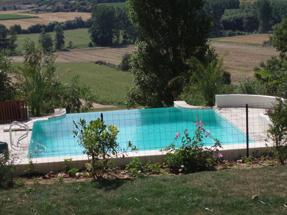 Inspiration for a mid-sized mediterranean rooftop rectangular infinity pool in Bordeaux with a water feature and natural stone pavers.