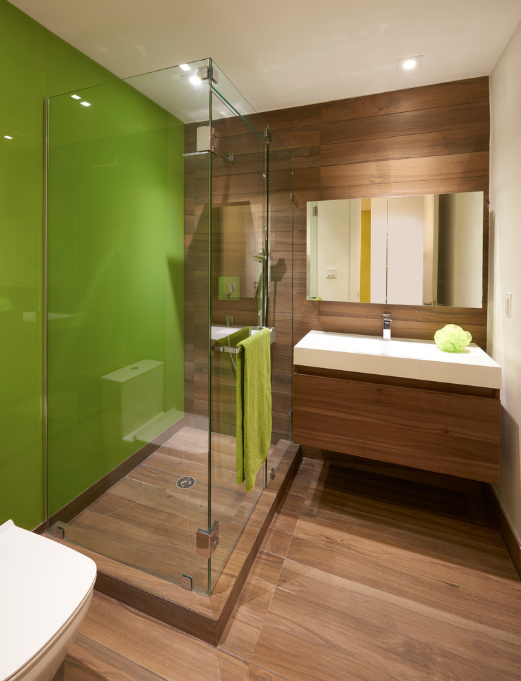 This is an example of a mid-sized contemporary kids bathroom in Miami with flat-panel cabinets, medium wood cabinets, a corner shower, a one-piece toilet, ceramic tile, orange walls, ceramic floors, a wall-mount sink and engineered quartz benchtops.