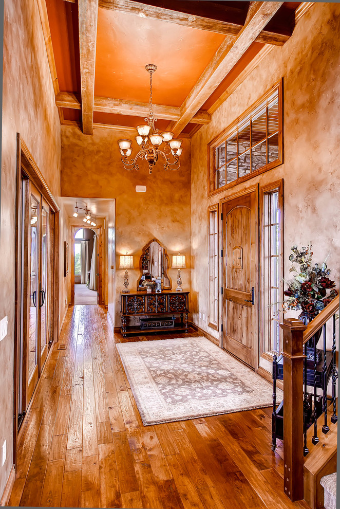 Example of a large medium tone wood floor foyer design in Denver with brown walls and a dark wood front door