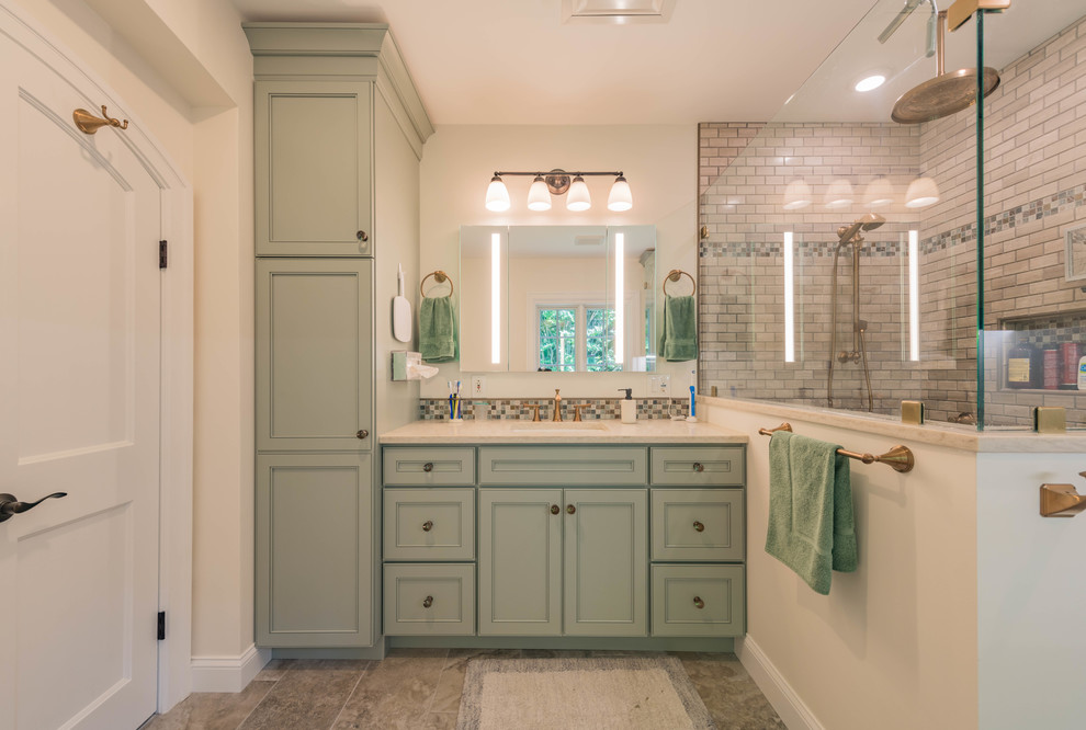 Mid-sized traditional master bathroom in Philadelphia with green cabinets, a corner shower, a one-piece toilet, beige tile, marble, grey walls, porcelain floors, an undermount sink, engineered quartz benchtops, beige floor, a hinged shower door, beige benchtops and recessed-panel cabinets.