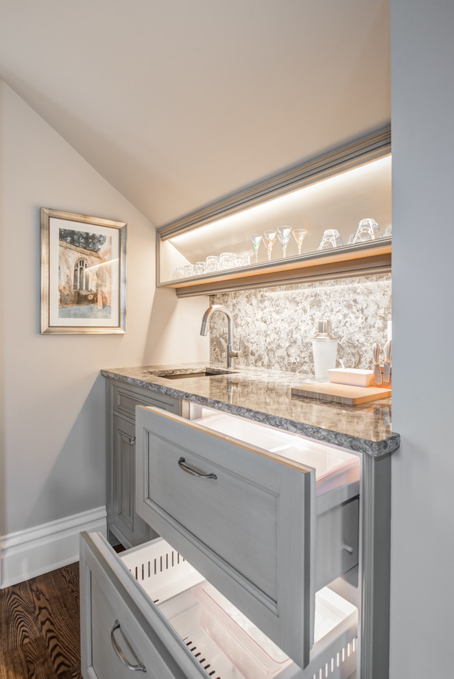 Small traditional single-wall wet bar in Seattle with an undermount sink, beaded inset cabinets, granite benchtops, stone slab splashback and medium hardwood floors.