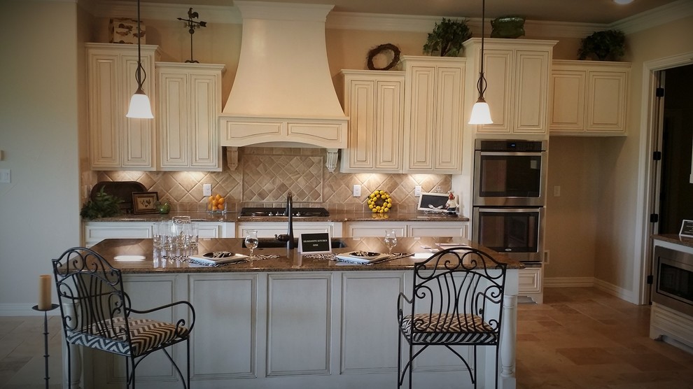 Mid-sized traditional l-shaped eat-in kitchen in Dallas with an undermount sink, raised-panel cabinets, white cabinets, granite benchtops, beige splashback, cement tile splashback, stainless steel appliances, with island and travertine floors.