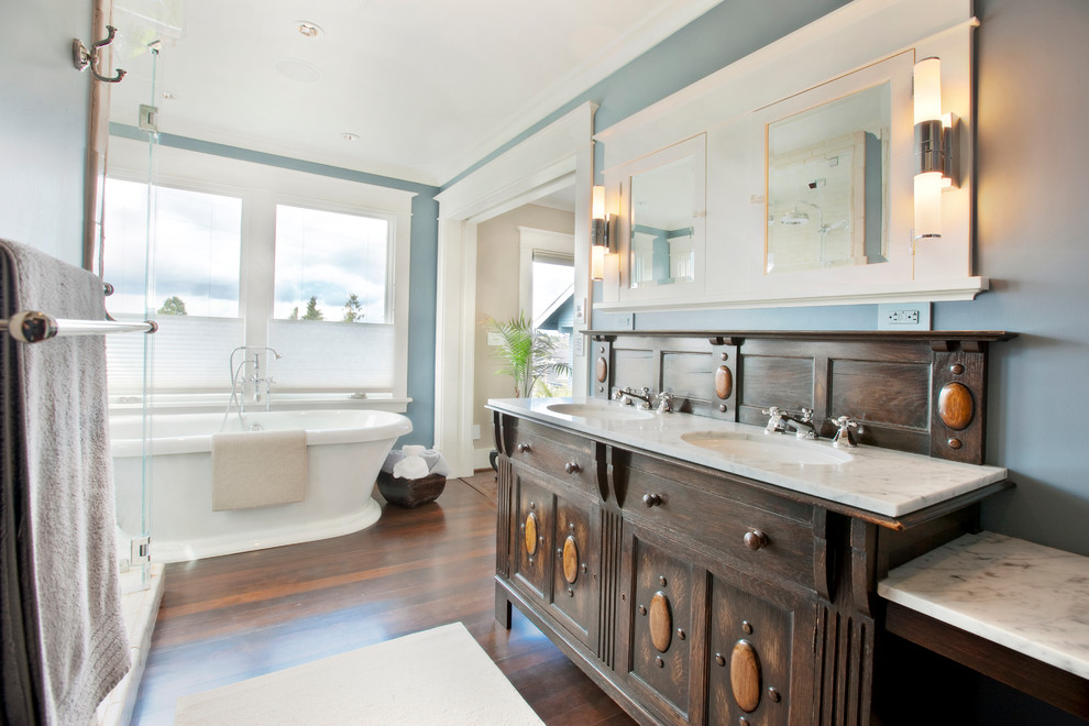 Elegant freestanding bathtub photo in Seattle with an undermount sink, furniture-like cabinets, dark wood cabinets and marble countertops