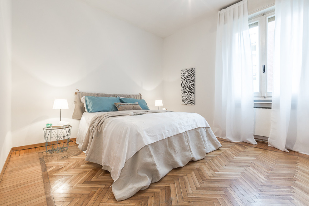 Large contemporary master bedroom in Bologna with white walls and medium hardwood floors.