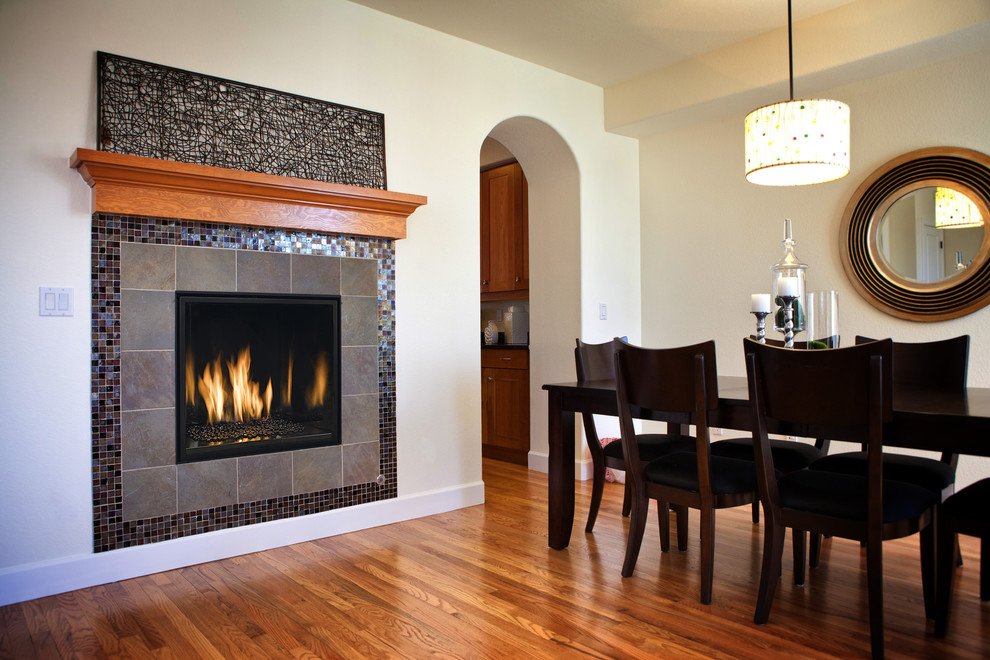 Photo of a large transitional separate dining room in Other with beige walls, medium hardwood floors, a standard fireplace, a tile fireplace surround and brown floor.