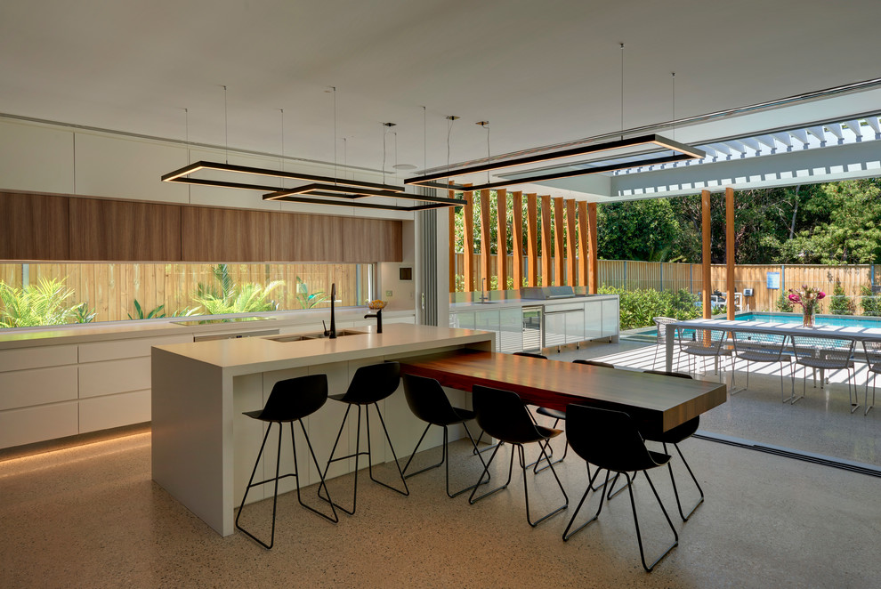 This is an example of a large contemporary single-wall eat-in kitchen in Sydney with white cabinets, stainless steel appliances, concrete floors, with island, a double-bowl sink, flat-panel cabinets, quartz benchtops and window splashback.