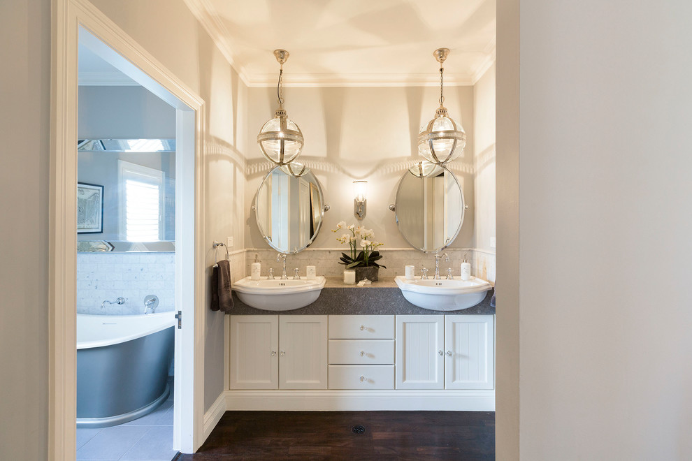 Inspiration for a large transitional master bathroom in Sydney with shaker cabinets, white cabinets, a freestanding tub, white tile, marble, grey walls, dark hardwood floors, an integrated sink and granite benchtops.