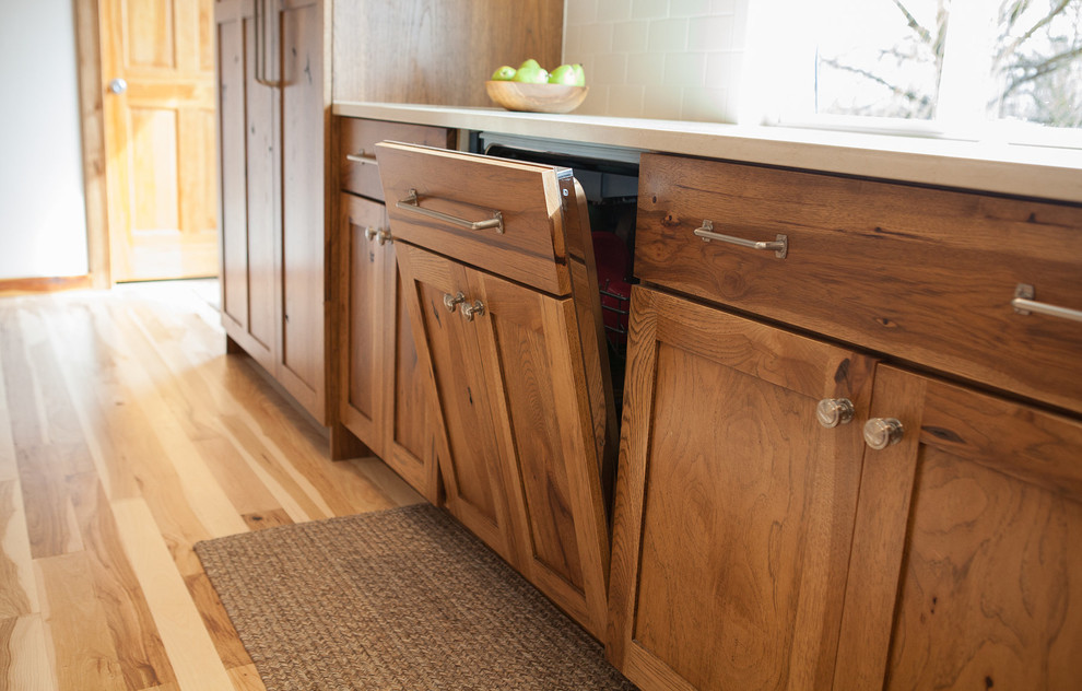 Inspiration for a mid-sized rustic l-shaped light wood floor eat-in kitchen remodel in Indianapolis with flat-panel cabinets, medium tone wood cabinets, quartz countertops, white backsplash, subway tile backsplash, paneled appliances, white walls, an island, an undermount sink and beige countertops