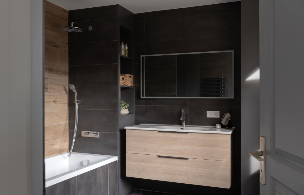 Idée de décoration pour une salle de bain principale minimaliste de taille moyenne avec un placard à porte affleurante, des portes de placard beiges, une baignoire encastrée, un combiné douche/baignoire, un carrelage noir, des dalles de pierre, un mur noir, un sol en ardoise, un plan de toilette en surface solide, un sol noir, un plan de toilette blanc, une fenêtre, meuble simple vasque et meuble-lavabo suspendu.