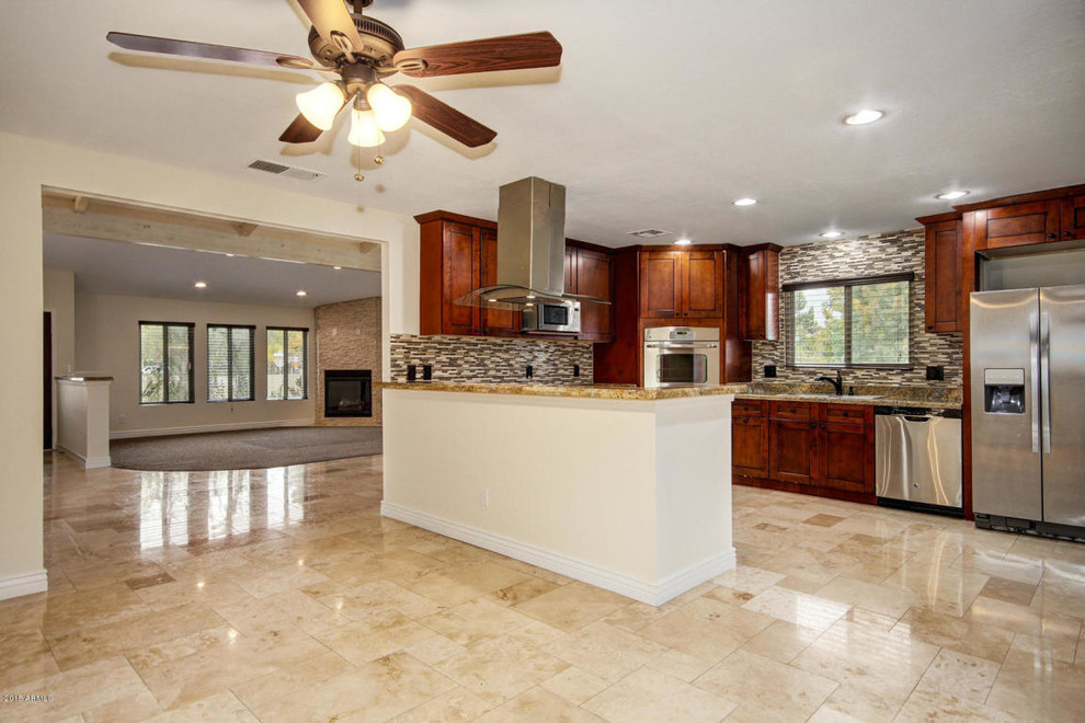 Inspiration for a large transitional u-shaped travertine floor and beige floor enclosed kitchen remodel in Phoenix with a drop-in sink, shaker cabinets, dark wood cabinets, granite countertops, multicolored backsplash, matchstick tile backsplash, stainless steel appliances, a peninsula and brown countertops