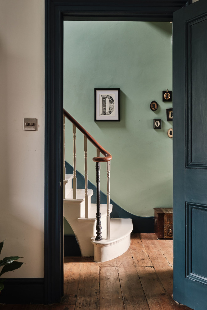 Medium sized eclectic hallway in London with green walls, medium hardwood flooring, a single front door and a black front door.