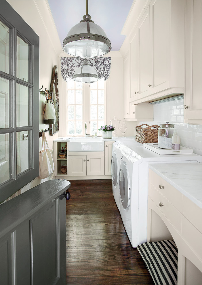 Photo of a traditional laundry room in Atlanta with beige cabinets, a farmhouse sink, brown floor and white benchtop.