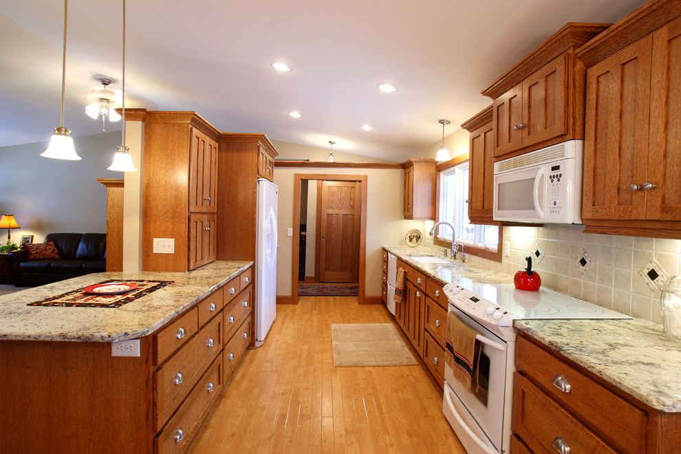 Photo of a mid-sized arts and crafts galley open plan kitchen in Minneapolis with an undermount sink, flat-panel cabinets, medium wood cabinets, laminate benchtops, beige splashback, ceramic splashback, white appliances and light hardwood floors.
