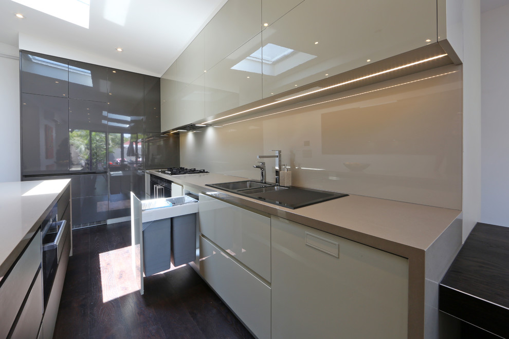 Photo of a contemporary galley eat-in kitchen in Melbourne with a drop-in sink, flat-panel cabinets, quartz benchtops, glass sheet splashback and stainless steel appliances.
