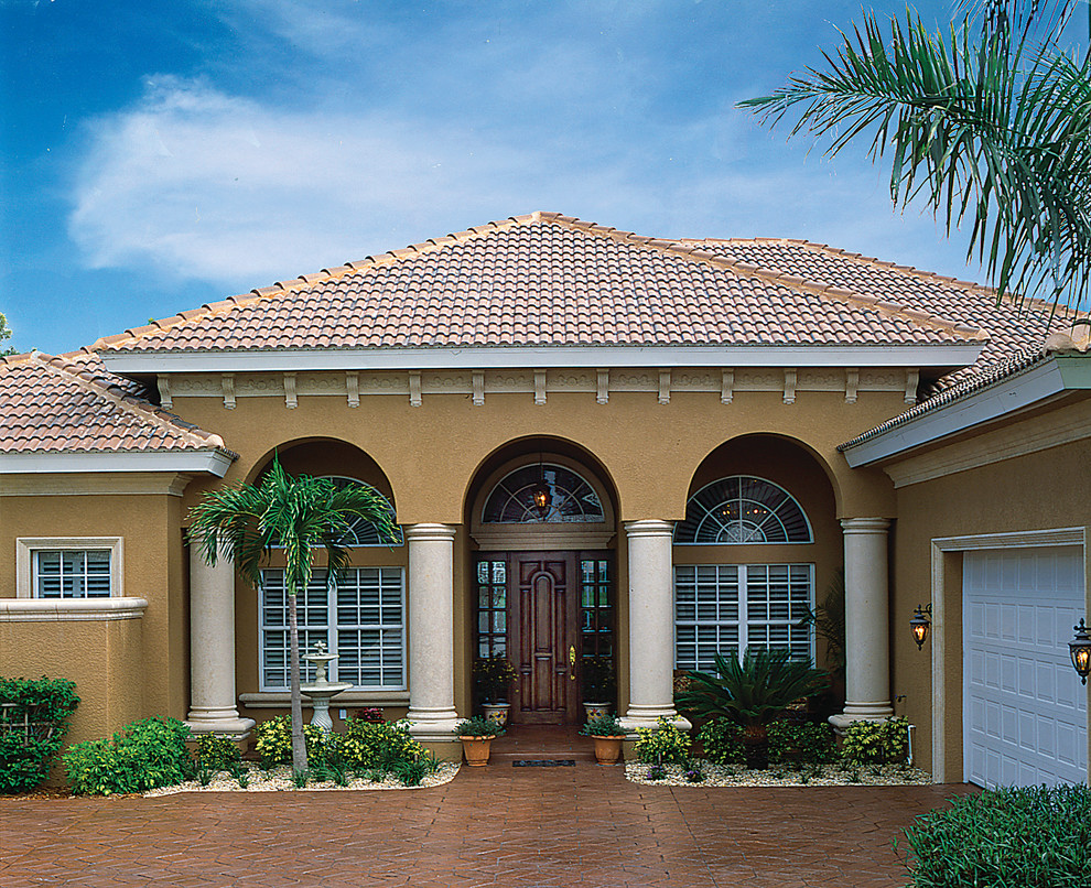 Photo of a mid-sized mediterranean one-storey stucco beige exterior in Miami with a hip roof.