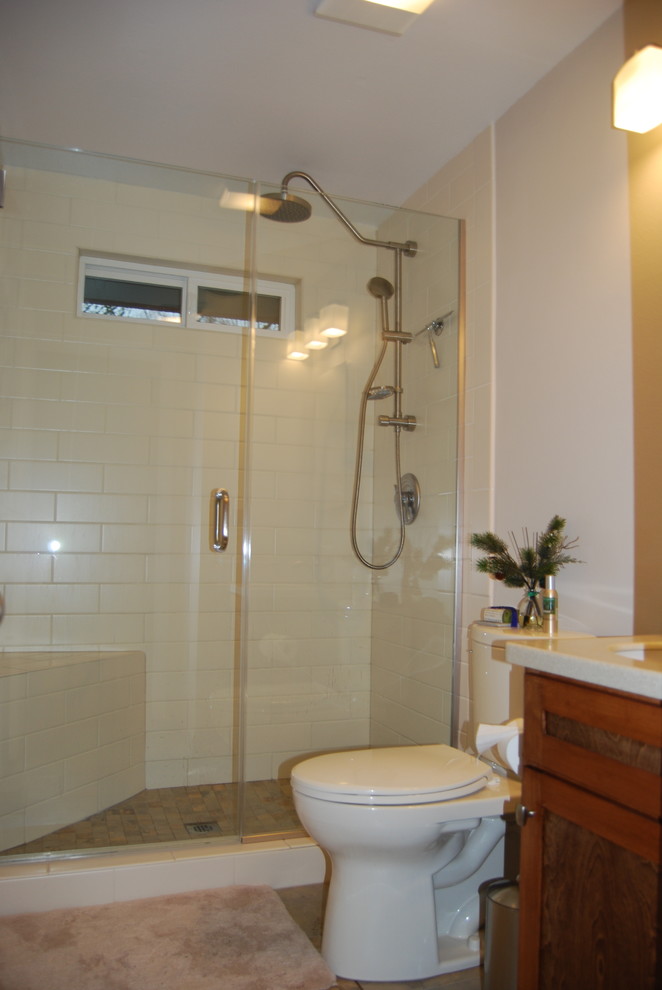 Mid-sized traditional 3/4 bathroom in Portland with shaker cabinets, beige walls, slate floors, an undermount sink, multi-coloured floor, dark wood cabinets, an alcove shower, a two-piece toilet, white tile, subway tile, solid surface benchtops and a hinged shower door.