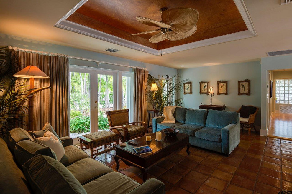 Photo of a mid-sized tropical open concept living room in Miami with blue walls and terra-cotta floors.