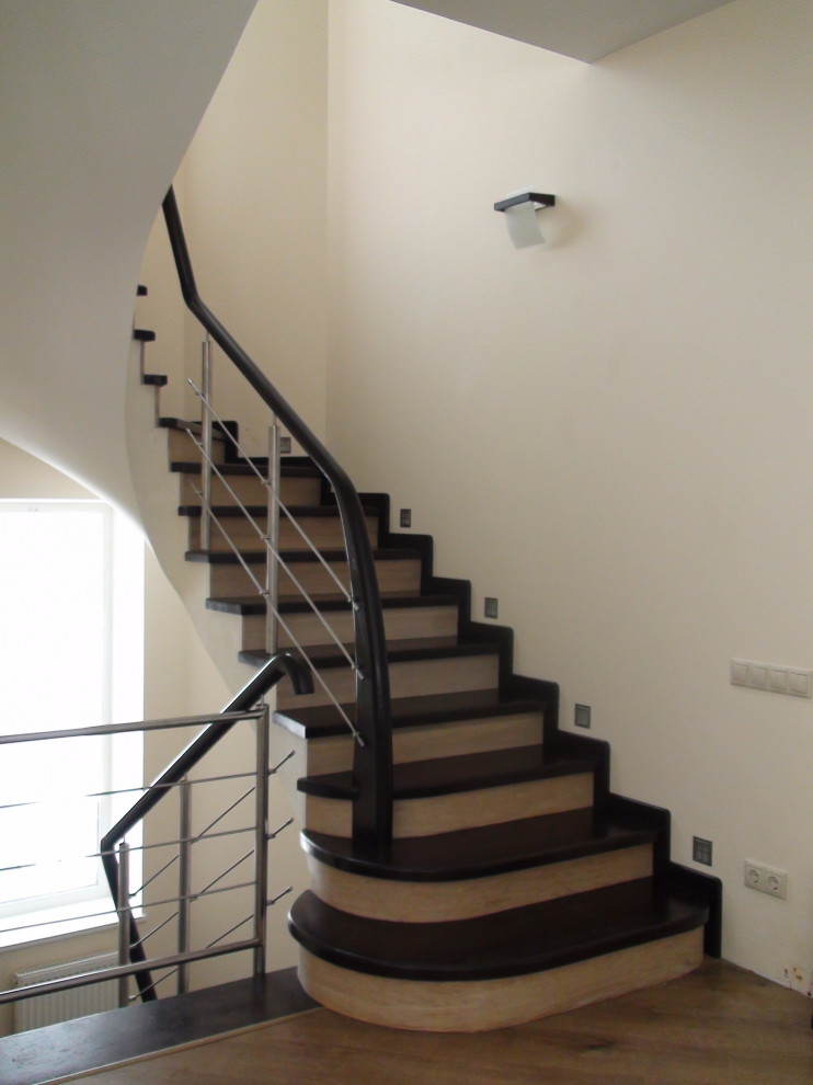 Idée de décoration pour un escalier courbe minimaliste de taille moyenne avec des marches en bois, des contremarches en bois, un garde-corps en métal et du papier peint.