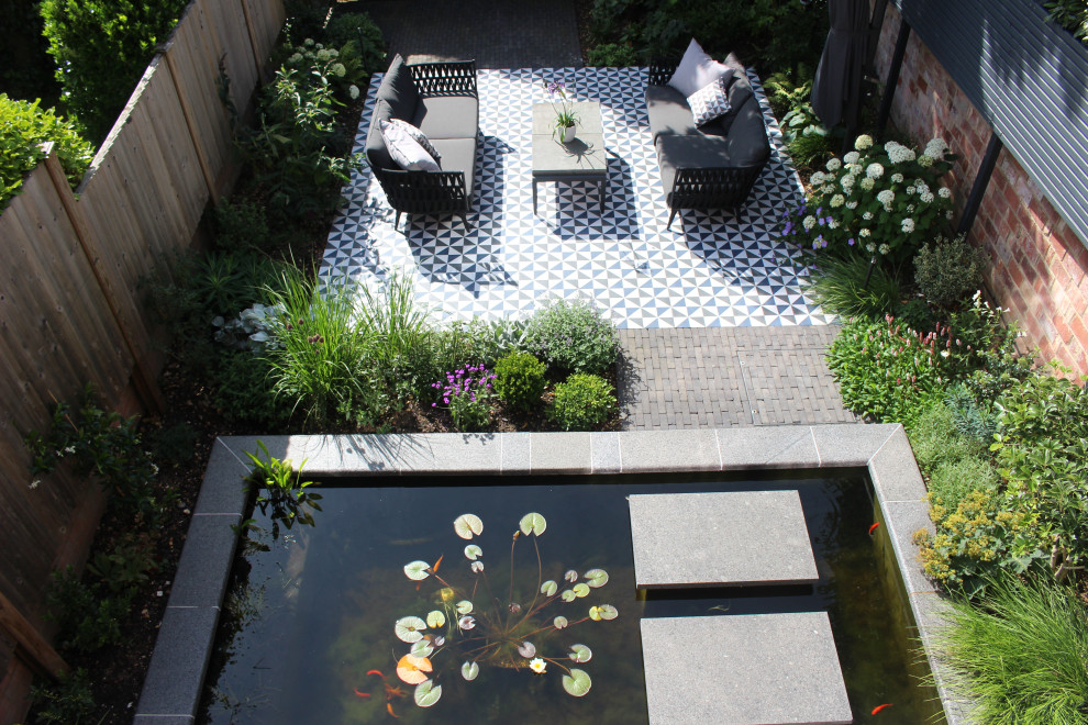 This is an example of a small contemporary courtyard patio in Hampshire with natural stone paving and an awning.