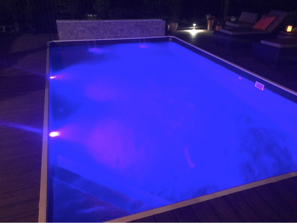 Inspiration for a large modern backyard rectangular aboveground pool fountain remodel in Detroit with decking