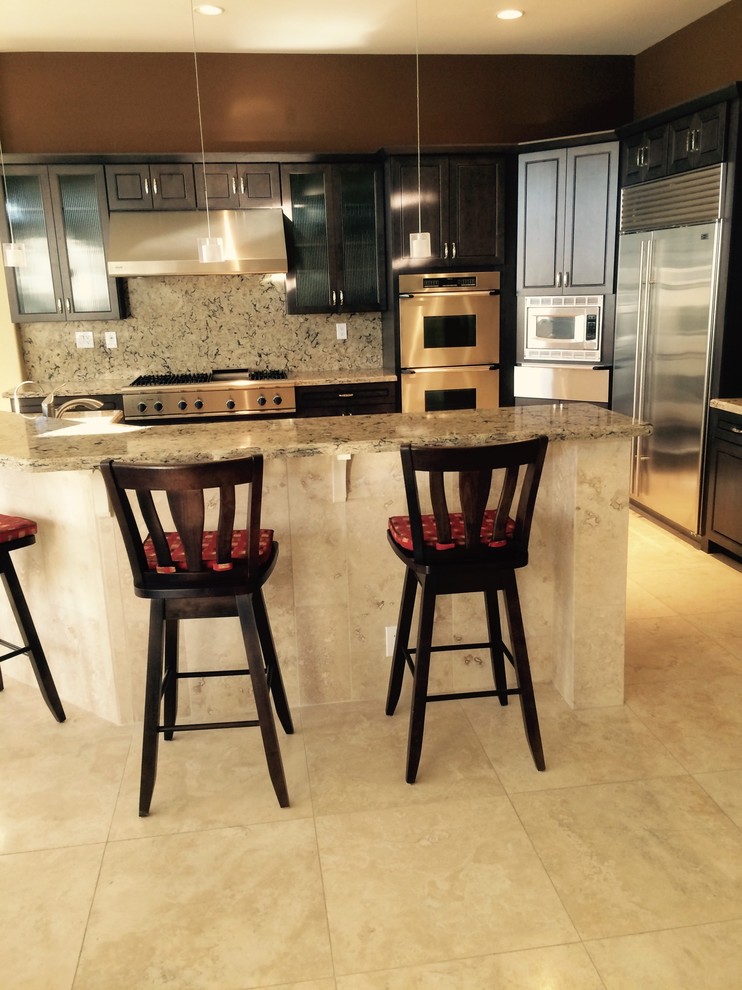 Large transitional l-shaped ceramic tile and beige floor kitchen photo in Phoenix with a double-bowl sink, raised-panel cabinets, dark wood cabinets, granite countertops, multicolored backsplash, stone slab backsplash, stainless steel appliances and an island