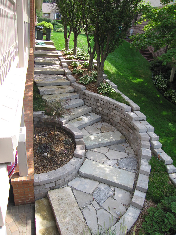 Traditional courtyard garden in Detroit with a retaining wall and natural stone pavers for summer.