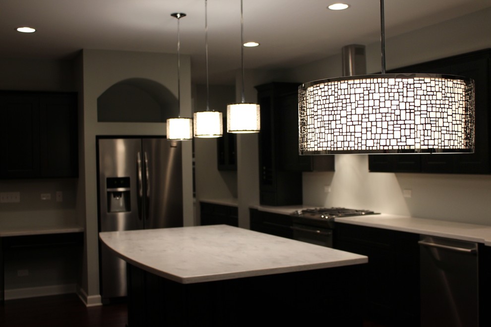 Enclosed kitchen - mid-sized transitional single-wall dark wood floor enclosed kitchen idea in Chicago with an undermount sink, recessed-panel cabinets, white cabinets, solid surface countertops, white backsplash, porcelain backsplash, stainless steel appliances and an island