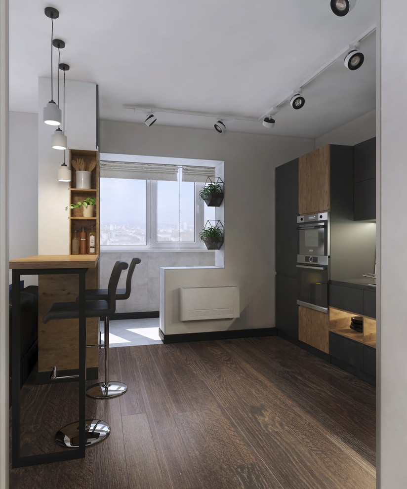 This is an example of a mid-sized contemporary l-shaped open plan kitchen in Other with an undermount sink, flat-panel cabinets, black cabinets, glass sheet splashback, medium hardwood floors, beige floor, panelled appliances and a peninsula.