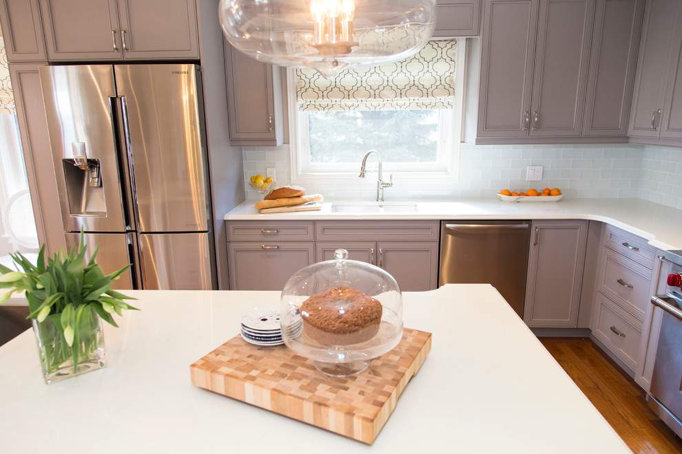 Inspiration for a mid-sized transitional u-shaped medium tone wood floor open concept kitchen remodel in Toronto with an undermount sink, recessed-panel cabinets, gray cabinets, quartzite countertops, white backsplash, stainless steel appliances and an island