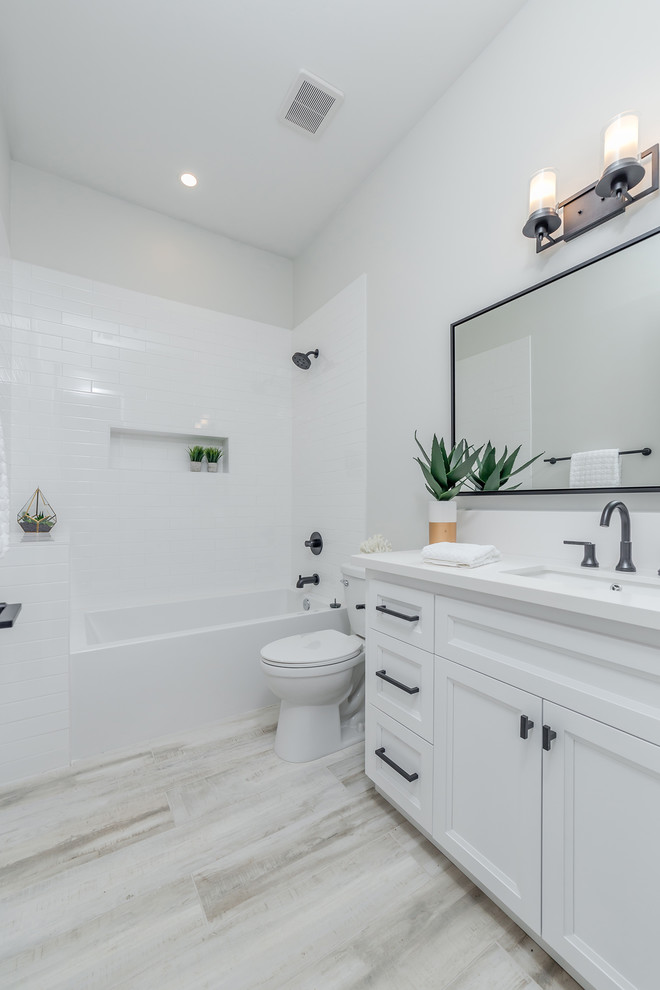 Small country 3/4 bathroom in Sacramento with beaded inset cabinets, white cabinets, a freestanding tub, a corner shower, a two-piece toilet, white tile, ceramic tile, grey walls, light hardwood floors, an integrated sink, granite benchtops, grey floor, a hinged shower door and white benchtops.