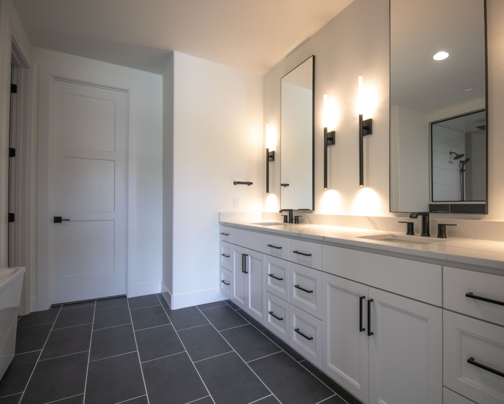 Classic ensuite bathroom in Omaha with white cabinets, a freestanding bath, a double shower, a one-piece toilet, white walls, porcelain flooring, a submerged sink, engineered stone worktops, a hinged door, an enclosed toilet, double sinks and a built in vanity unit.