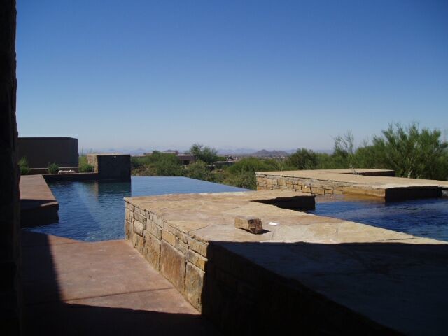 Example of a mid-sized backyard stamped concrete and rectangular infinity hot tub design in Phoenix