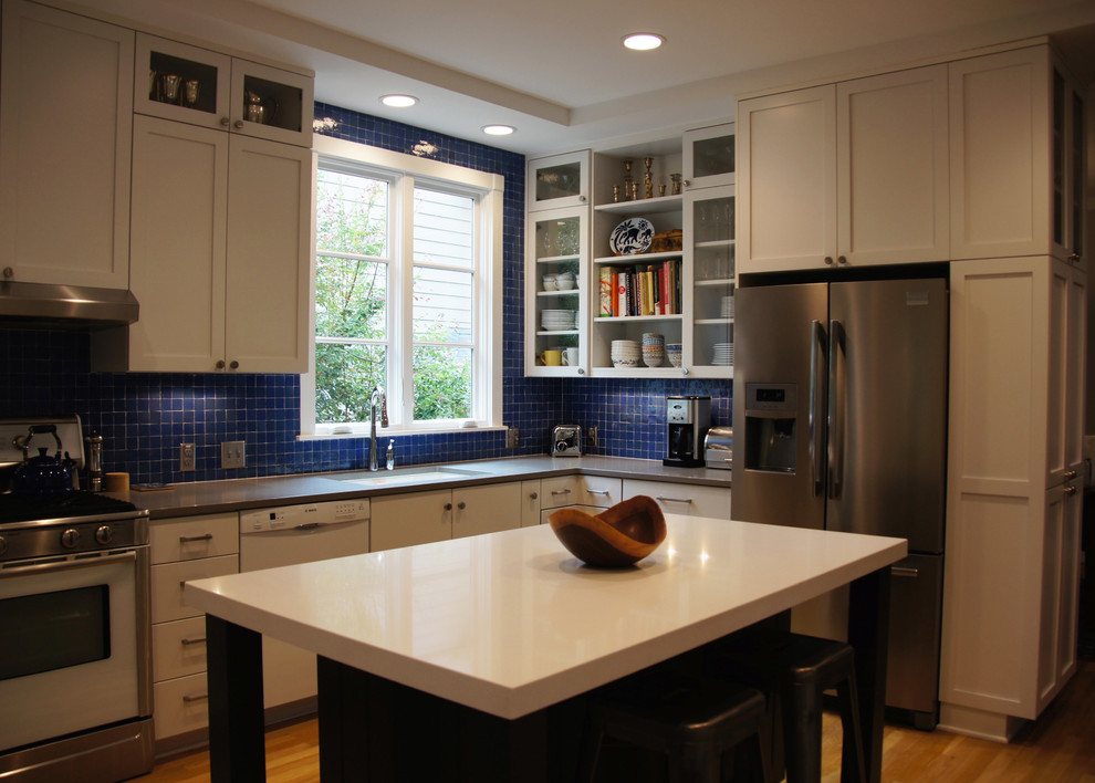 Trendy light wood floor open concept kitchen photo in Raleigh with a single-bowl sink, shaker cabinets, white cabinets, recycled glass countertops, blue backsplash, ceramic backsplash, stainless steel appliances and an island