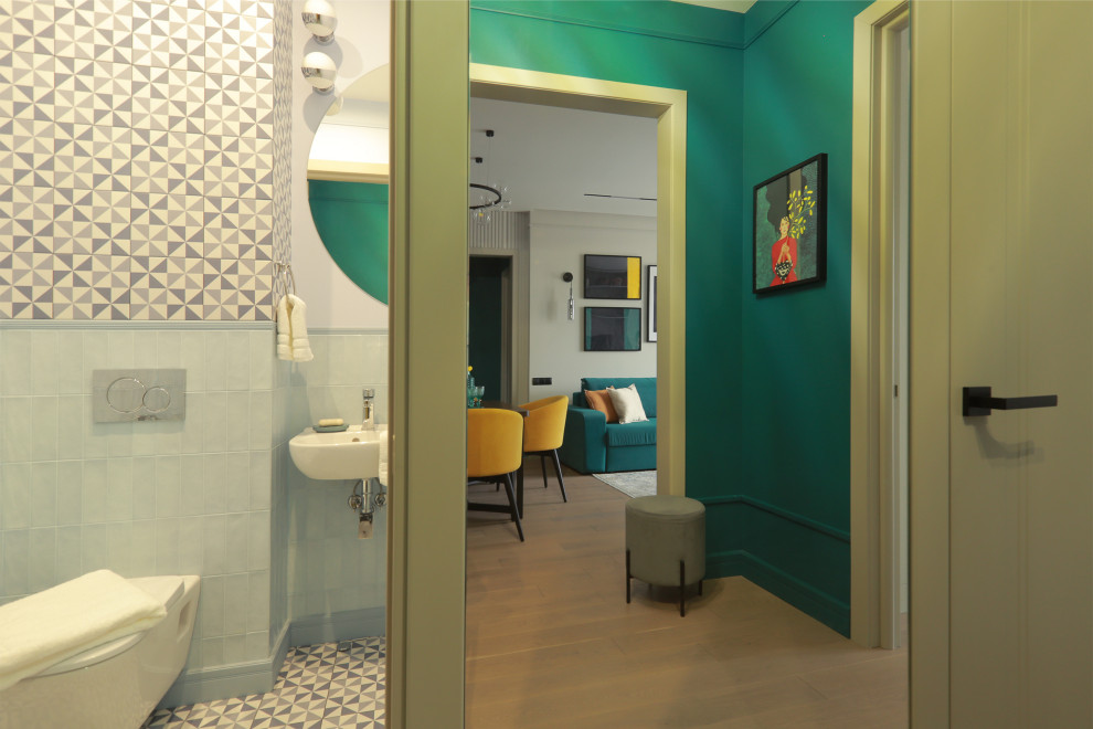 Kleine Gästetoilette mit Wandtoilette, blauen Fliesen, Porzellanfliesen, blauer Wandfarbe, Porzellan-Bodenfliesen, Wandwaschbecken und buntem Boden in Moskau