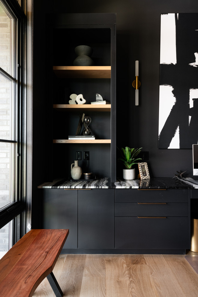 Ejemplo de despacho minimalista de tamaño medio con paredes negras, suelo de madera clara, escritorio empotrado y suelo marrón