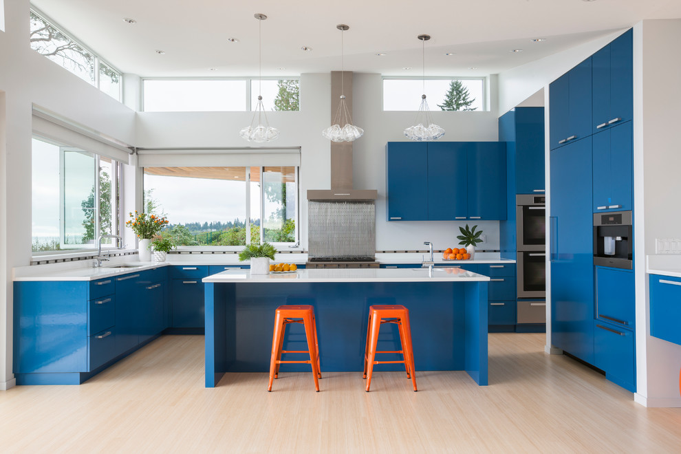 Inspiration for a mid-sized contemporary u-shaped open plan kitchen in Seattle with an undermount sink, flat-panel cabinets, blue cabinets, metallic splashback, stainless steel appliances, light hardwood floors, solid surface benchtops, metal splashback, with island and beige floor.