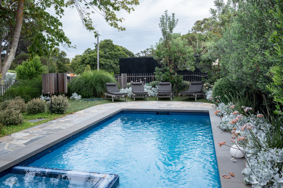 This is an example of a transitional rectangular pool in Melbourne with a hot tub and natural stone pavers.