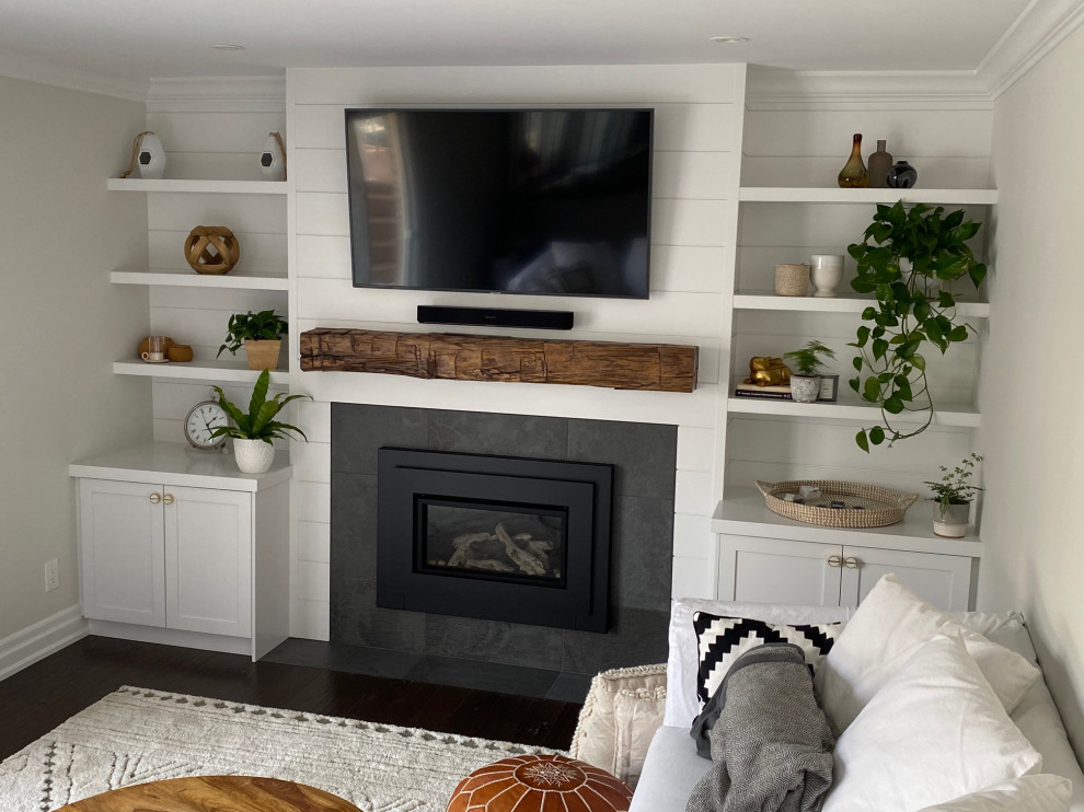 This is an example of a mid-sized contemporary enclosed family room in Toronto with grey walls, dark hardwood floors, a standard fireplace, a wall-mounted tv, brown floor and planked wall panelling.