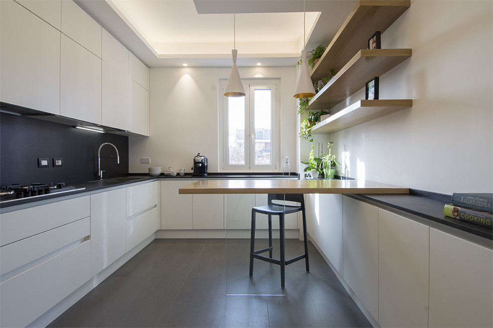 Photo of an expansive contemporary u-shaped open plan kitchen in Rome with quartz benchtops, black splashback, stainless steel appliances, porcelain floors, grey floor, black benchtop, flat-panel cabinets and white cabinets.