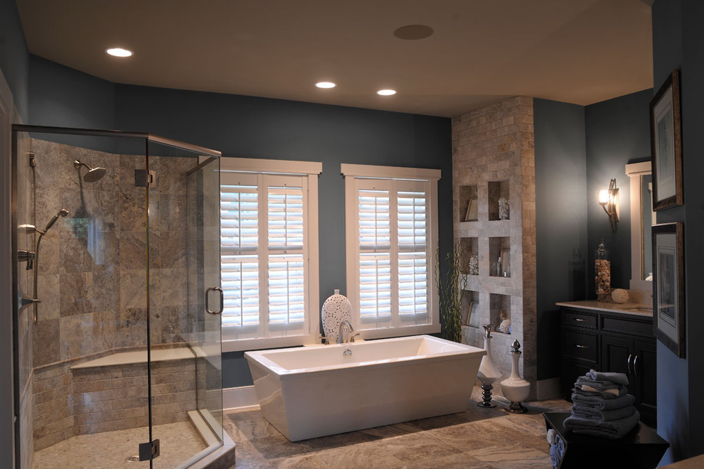 This is an example of a contemporary master bathroom in Columbus with a freestanding tub, beaded inset cabinets, dark wood cabinets, a corner shower, beige tile, stone tile, blue walls, an undermount sink, brown floor, a hinged shower door, a double vanity and a built-in vanity.