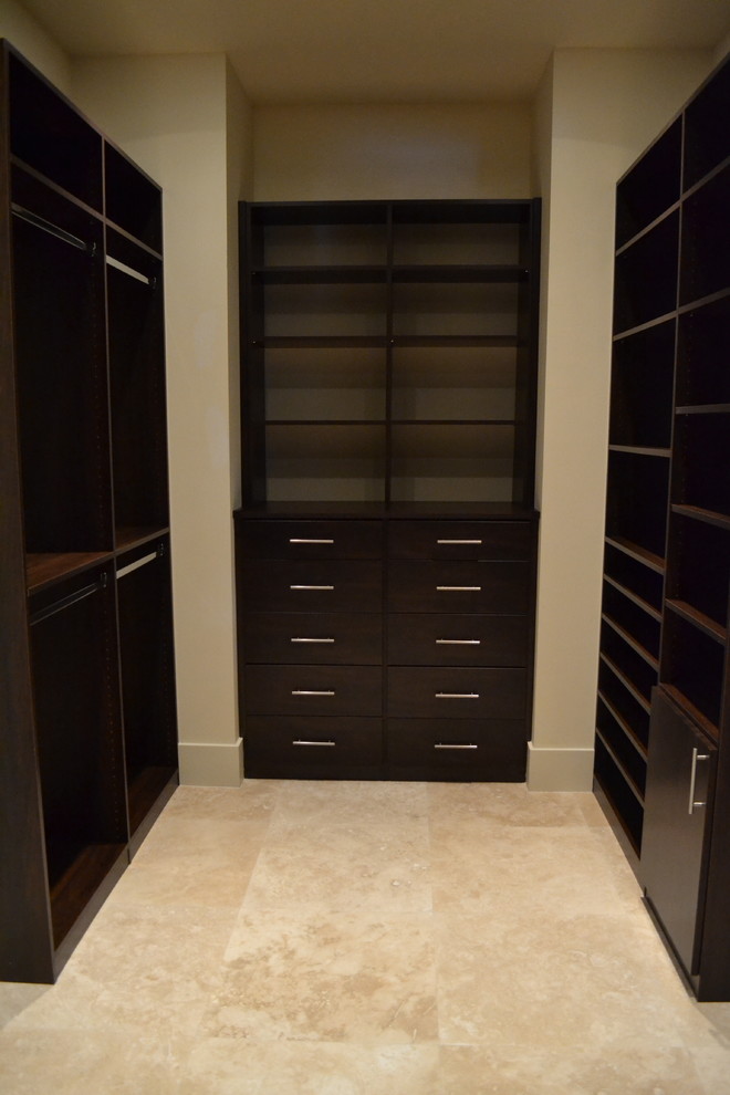 Inspiration for a mid-sized contemporary walk-in wardrobe in Orlando with dark wood cabinets, flat-panel cabinets, travertine floors and beige floor.