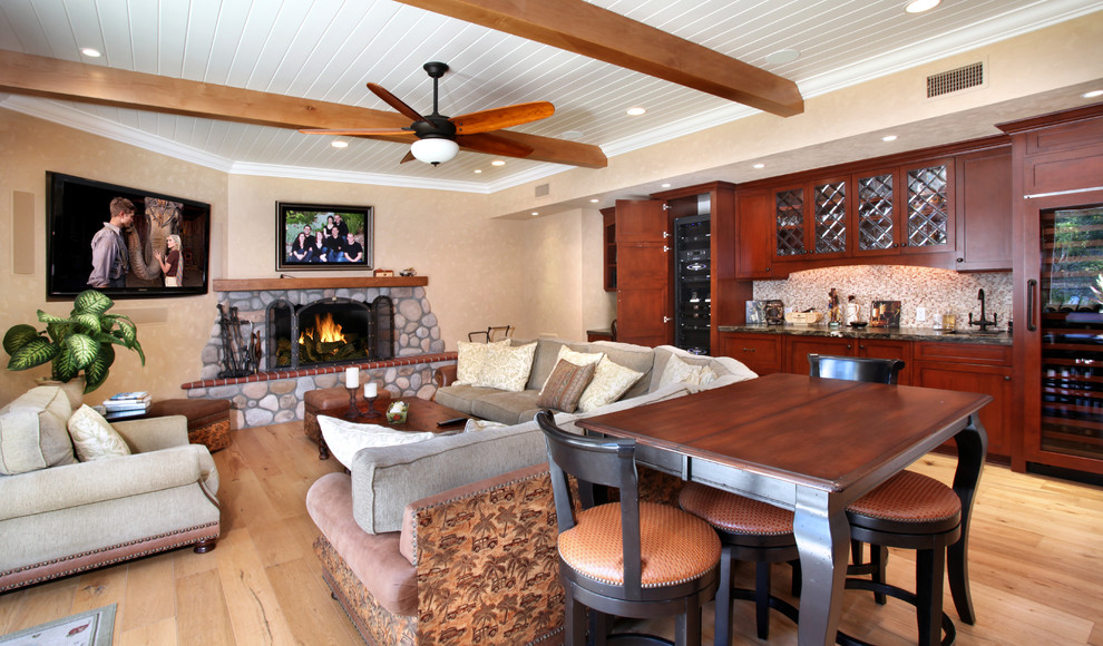 This is an example of a traditional family room in Orange County with beige walls, light hardwood floors, a standard fireplace, a stone fireplace surround and a wall-mounted tv.