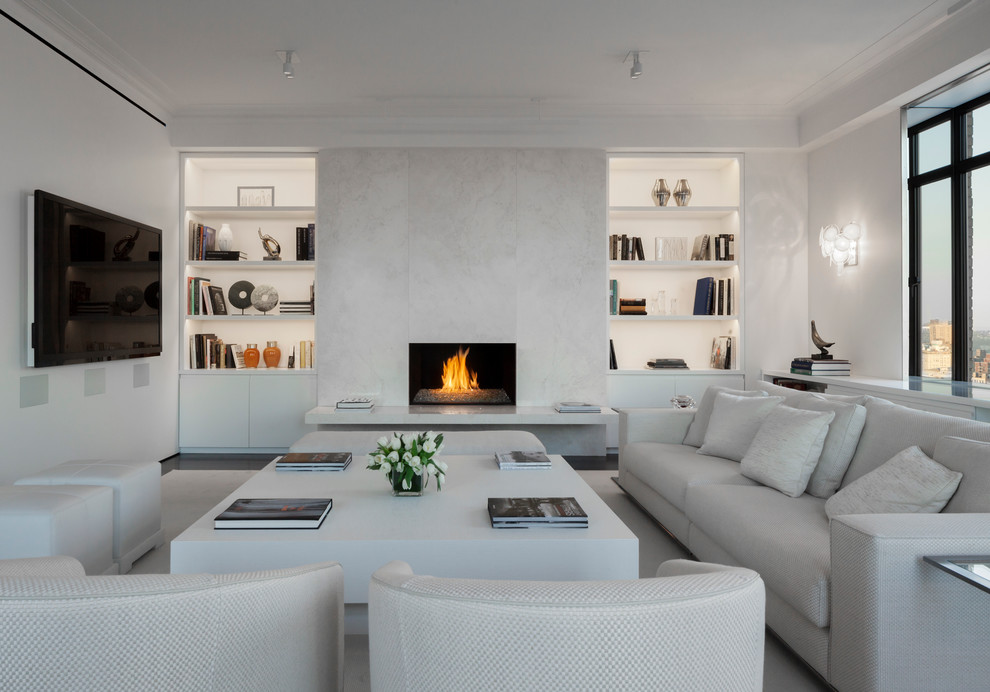 Photo of a contemporary family room in New York with a library, a standard fireplace and a wall-mounted tv.