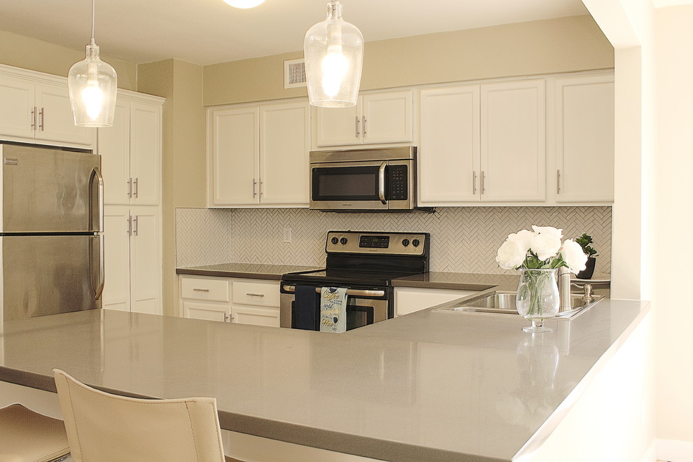 Example of a small transitional l-shaped terra-cotta tile eat-in kitchen design in Phoenix with a drop-in sink, shaker cabinets, white cabinets, quartzite countertops, white backsplash, mosaic tile backsplash, stainless steel appliances and a peninsula