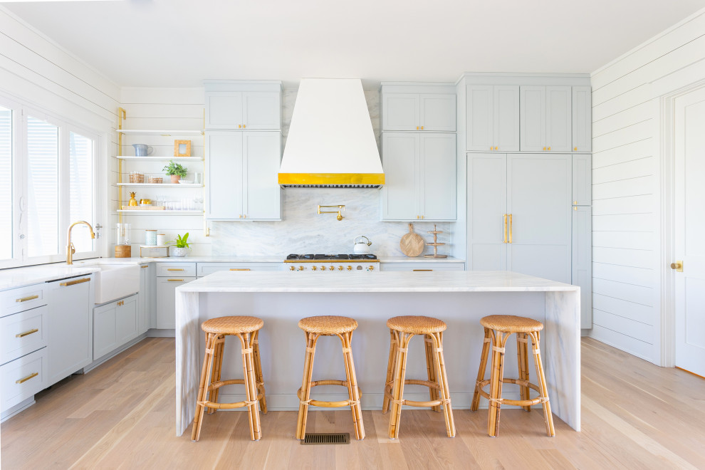 Inspiration for a large coastal l-shaped light wood floor and brown floor open concept kitchen remodel in Charleston with a farmhouse sink, shaker cabinets, blue cabinets, marble countertops, blue backsplash, stone slab backsplash, paneled appliances, an island and blue countertops