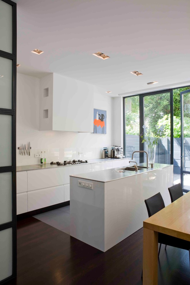 Modern eat-in kitchen in New York with a double-bowl sink, flat-panel cabinets, white cabinets and white splashback.