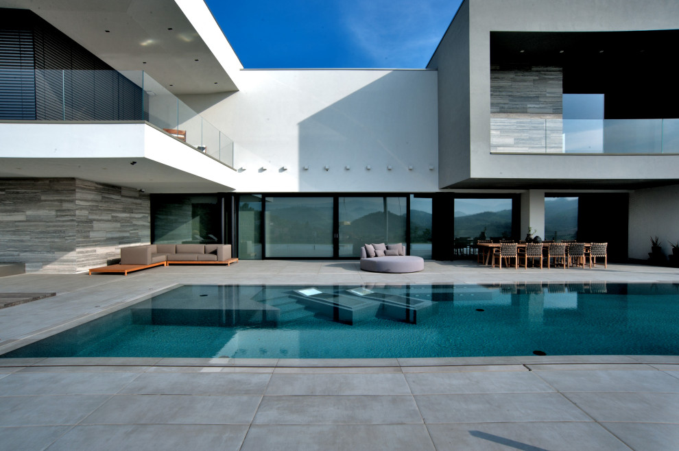 Imagen de piscina moderna rectangular con paisajismo de piscina y suelo de baldosas