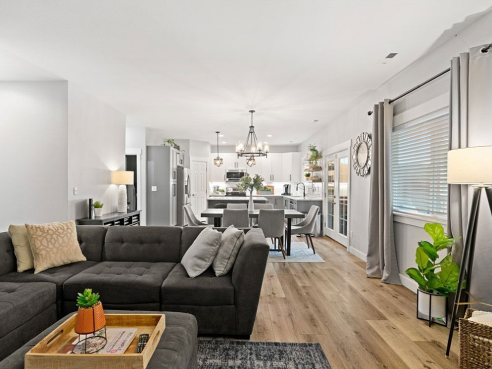 Cette photo montre un grand salon ouvert avec un mur gris, parquet clair, un sol marron, un plafond en papier peint et du papier peint.