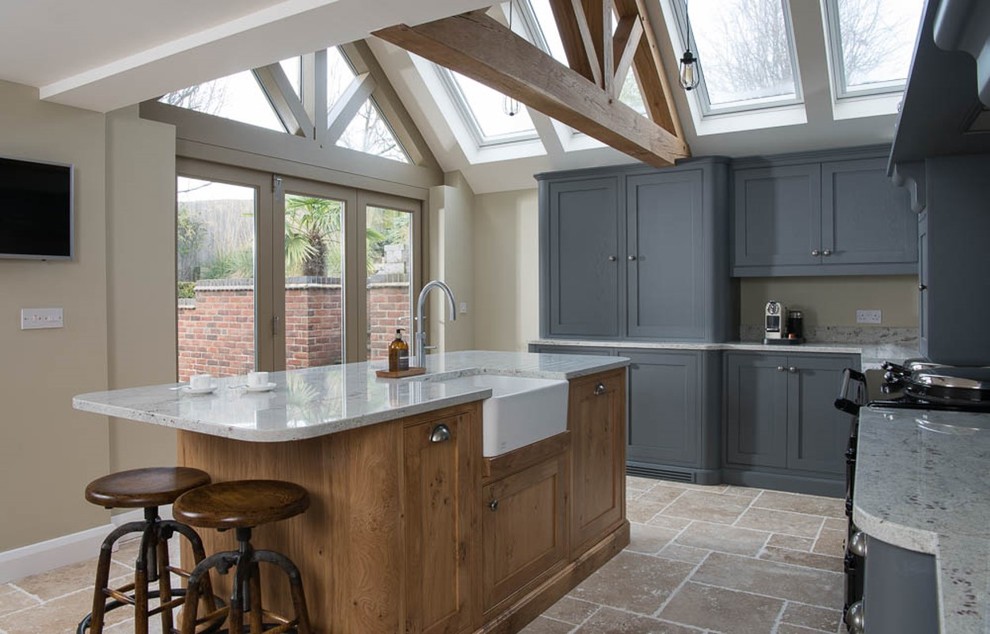 This is an example of a large country l-shaped kitchen pantry in Other with a farmhouse sink, shaker cabinets, grey cabinets, granite benchtops, white splashback, stone slab splashback, limestone floors and with island.